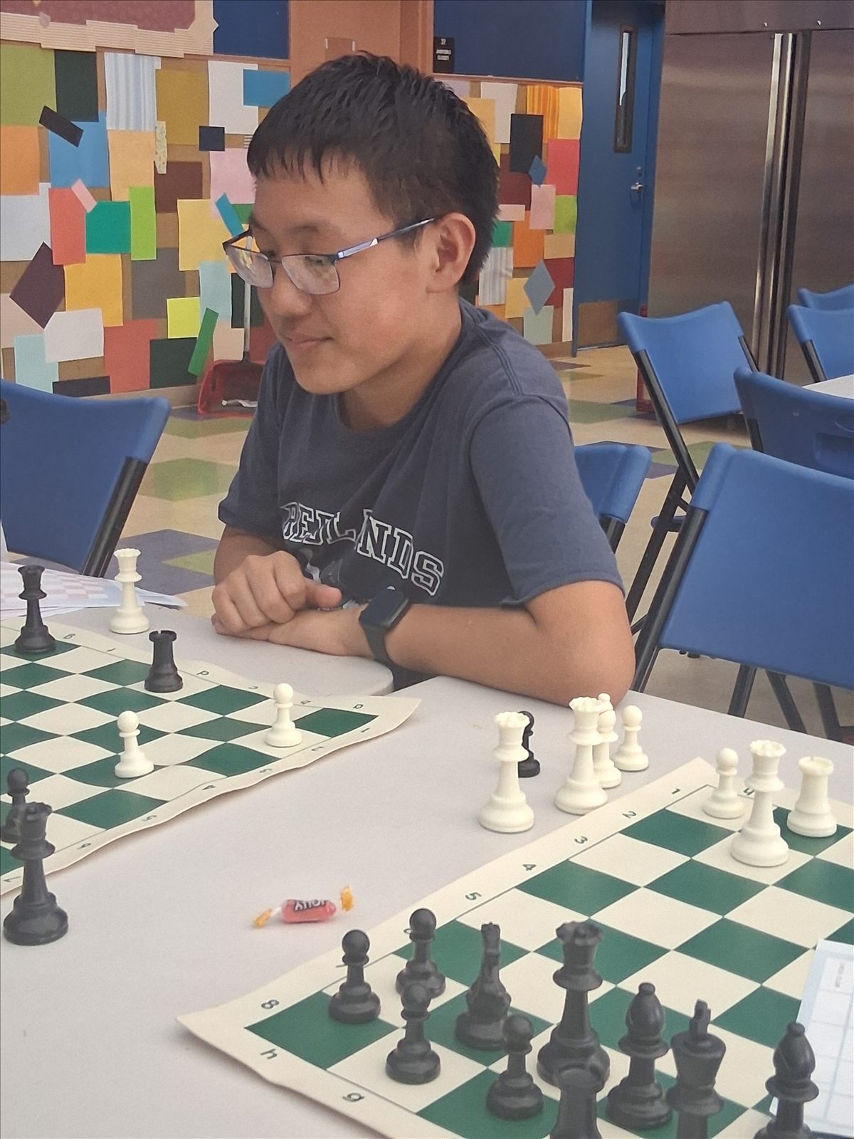 A young club member leaning over a giant chessboard mid-game at the Redlands Boys & Girls Club.