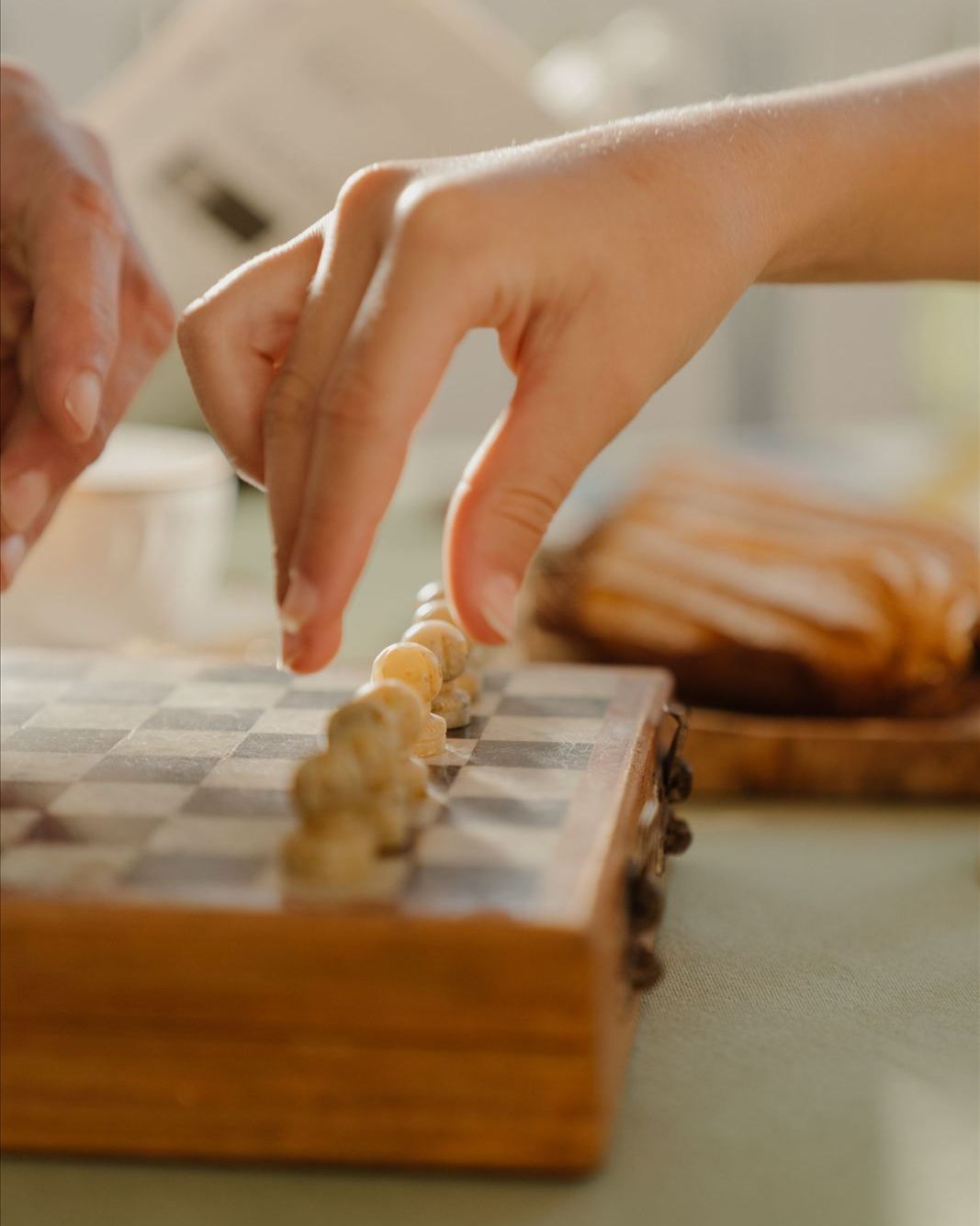 A close-up of a hand setting up white chess pieces on a board, evoking the program's early days.