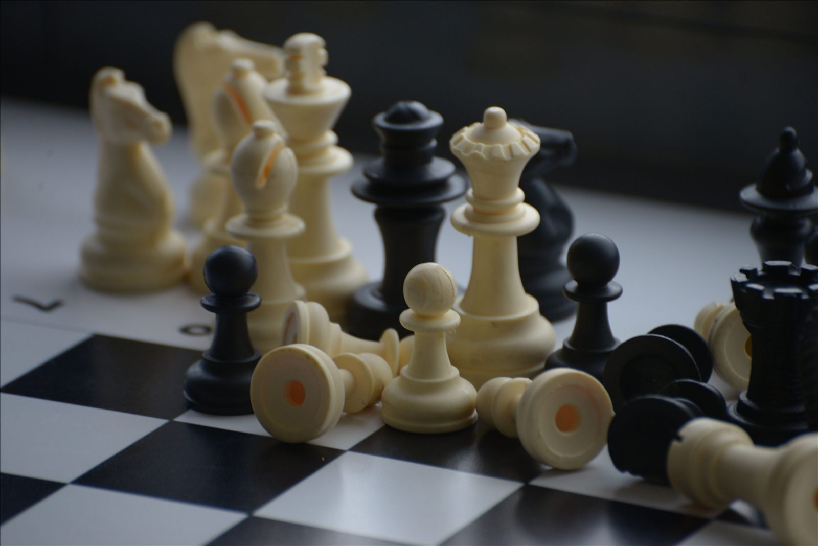 Chess pieces scattered and knocked over on the board at the end of a game.